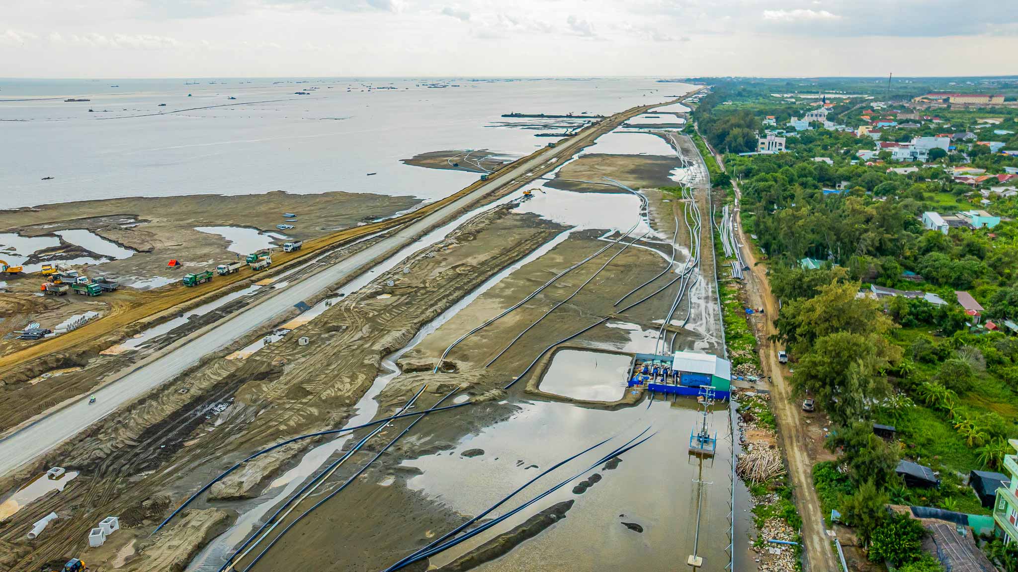Nhiều tuyến ống dẫn luồng hoạt động liên tục, ngoài xa hàng trăm sà lan bơm cát ngày đêm, khiến hình hài bờ kè và mặt bằng lấn biển dần hiện rõ.